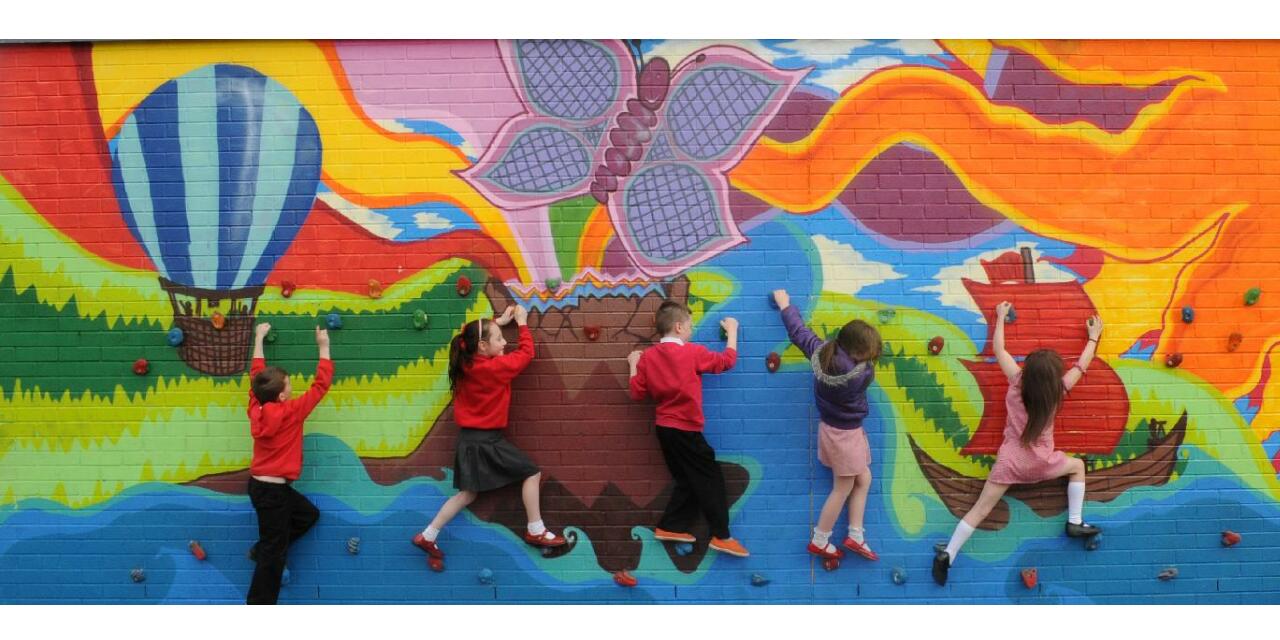 School children climbing a brightly coloured mural.