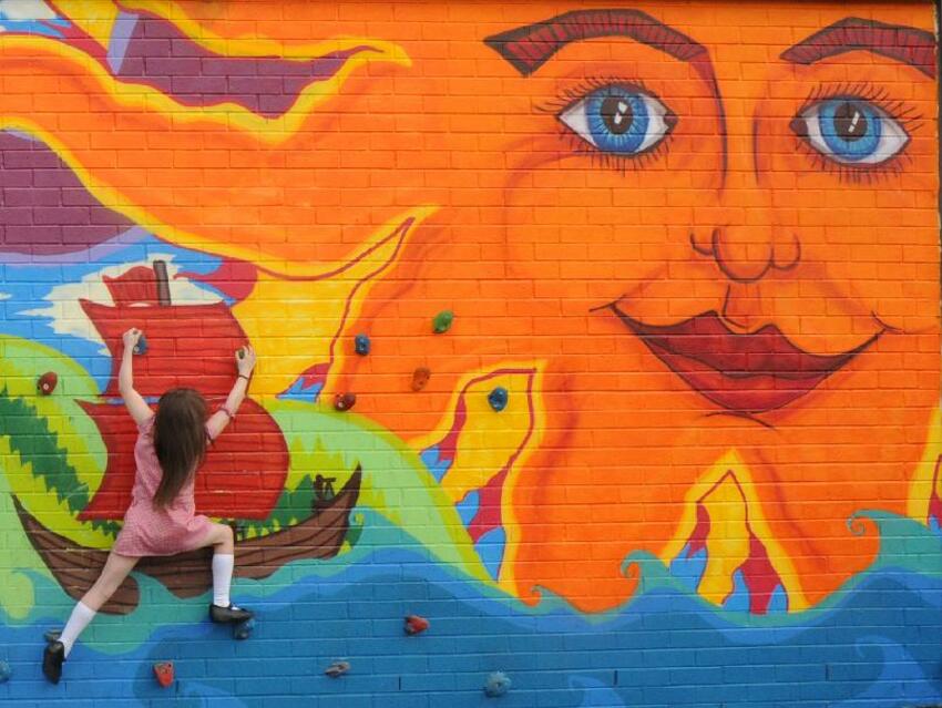 School children climbing a brightly coloured mural.