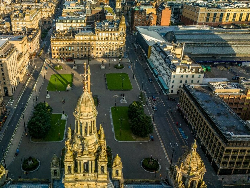 An aerial view looking over the spires of Glasgow City Chambers to George Square and the city centre beyond.